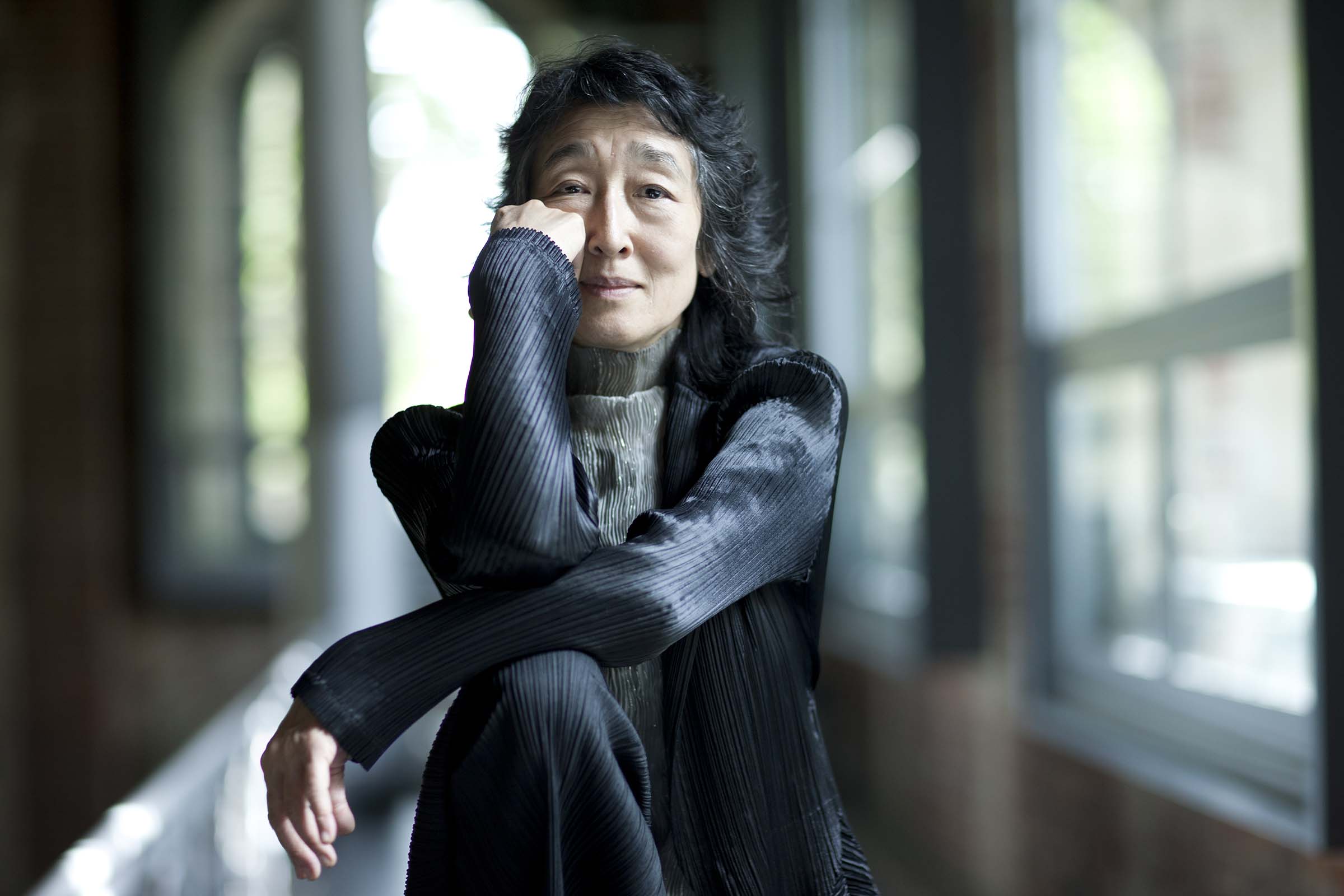 Mitsuko Uchida sitting with chin in hand.
